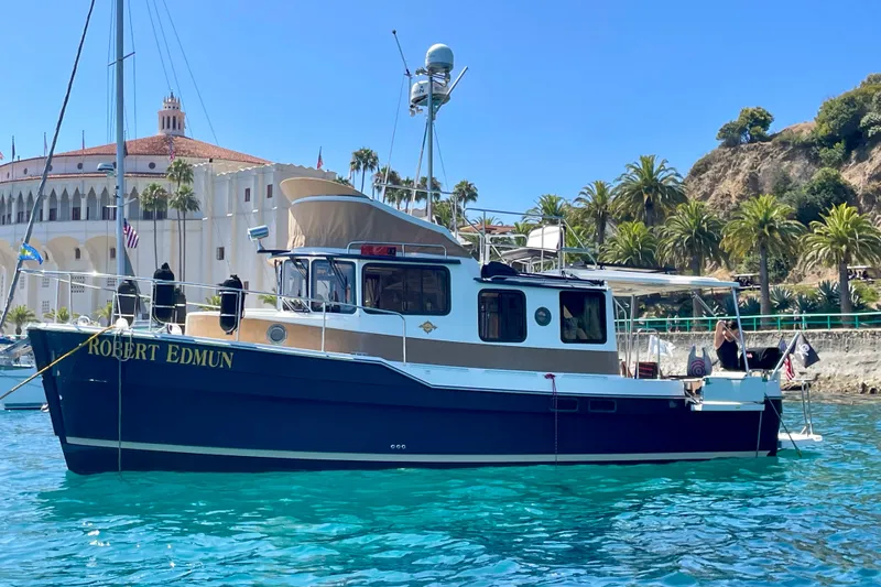 Slide: The Image of 2016 Ranger Tugs R-31 CB boat on clear blue water near a coastal building. - 12