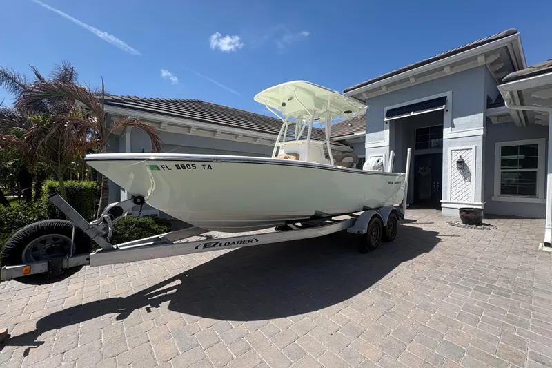 Slide: The Image of 2022 Sea Born LX22 Center Console boat on trailer in driveway, sunny day. - 3