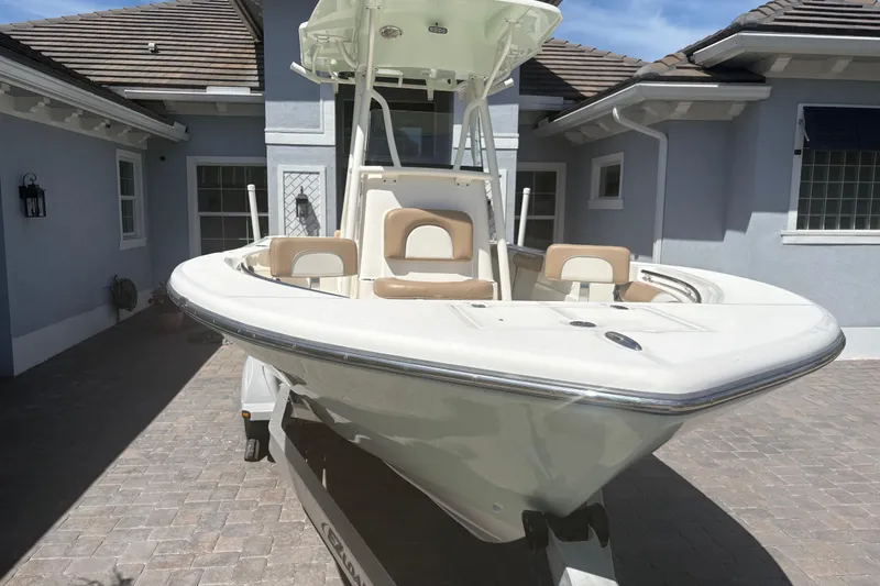 Slide: The Image of 2022 Sea Born LX22 Center Console boat with seating and storage, parked near a house. - 30