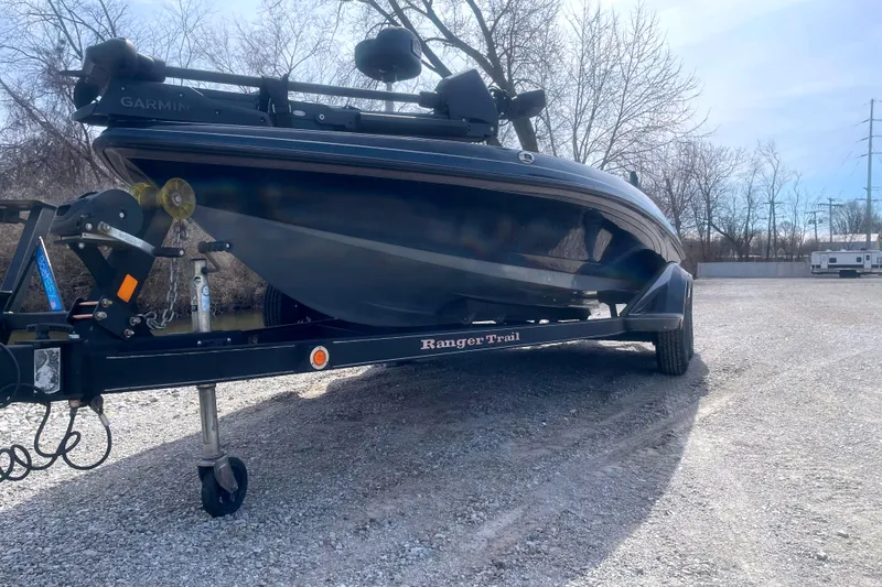 Slide: The Image of 2017 Ranger Z520 boat on trailer in gravel lot, surrounded by trees. - 12