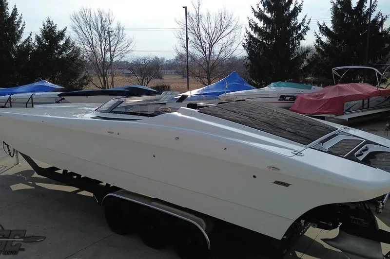 Slide: The Image of 2009 Nordic 36 Hurricane speedboat on trailer, parked outdoors with covered boats nearby. - 57