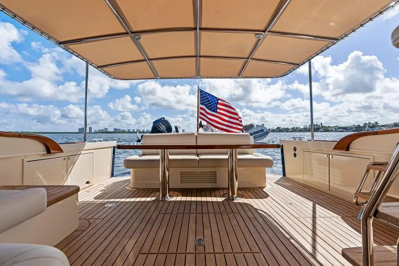 Slide: The Image of 2018 Palm Beach Motor Yachts PB55 Flybridge, spacious deck with seating, American flag, ocean view. - 1