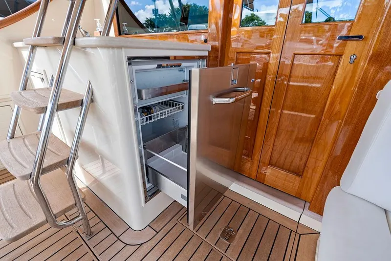 Slide: The Image of 2018 Palm Beach Motor Yachts PB55 Flybridge with open fridge, wooden deck, and stairs. - 10