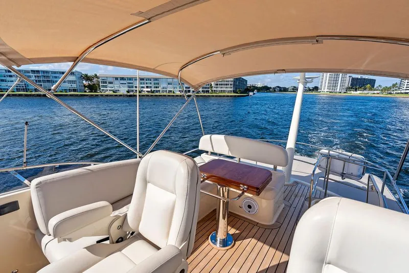 Slide: The Image of 2018 Palm Beach Motor Yachts PB55 Flybridge, luxurious deck view with seating and water backdrop. - 26