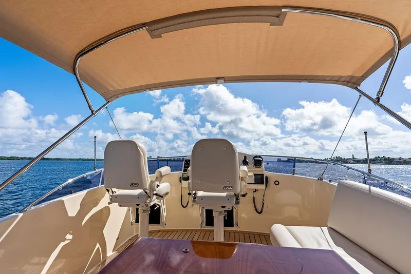 Slide: The Image of Flybridge view of 2018 Palm Beach Motor Yachts PB55, featuring helm seats and ocean backdrop. - 4