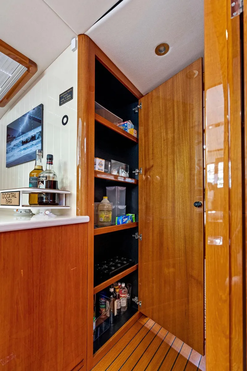 Slide: The Image of 2018 Palm Beach Motor Yachts PB55 Flybridge interior with wooden cabinetry and stocked shelves. - 46