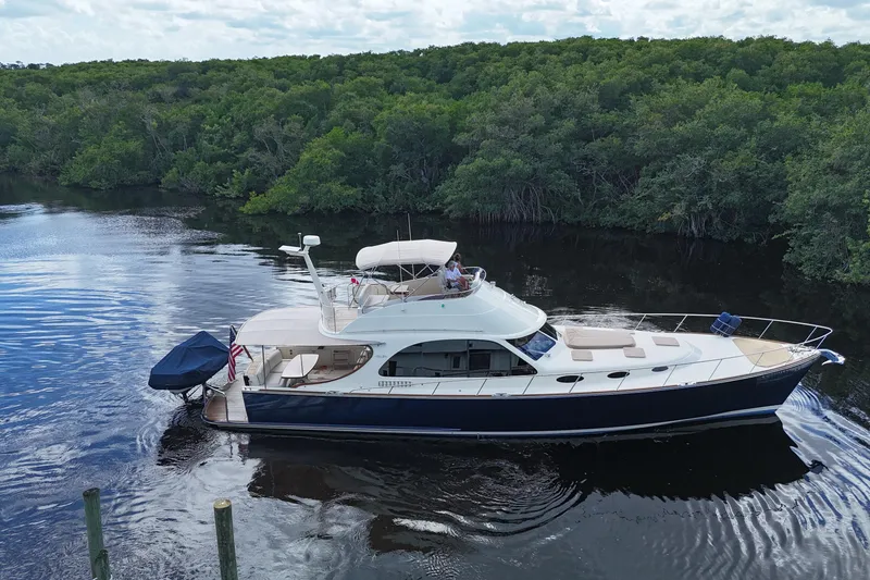 Slide: The Image of 2018 Palm Beach Motor Yachts PB55 Flybridge cruising on a serene river, surrounded by lush greenery. - 5