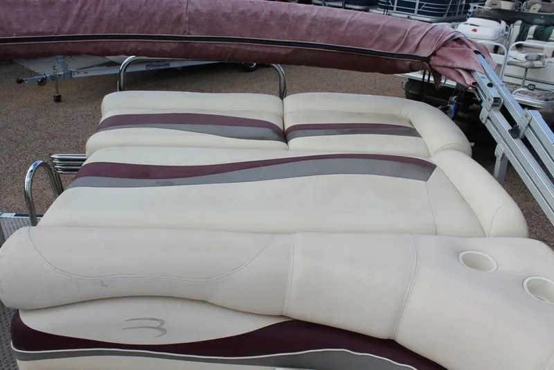 Slide: The Image of 2005 Bennington 2275 RL boat seating with beige and maroon upholstery, featuring cup holders. - 14