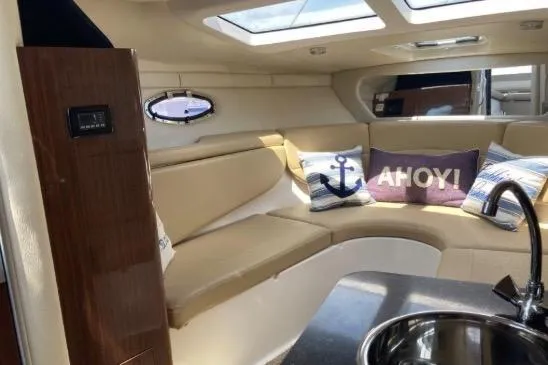 Slide: The Image of Interior of 2013 Regal 30 Express boat with cozy seating and nautical-themed pillows. - 26