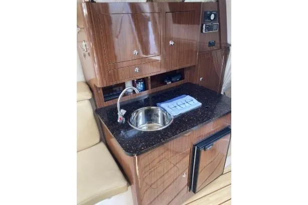 Slide: The Image of 2013 Regal 30 Express yacht interior with kitchenette, sink, and wooden cabinetry. - 28