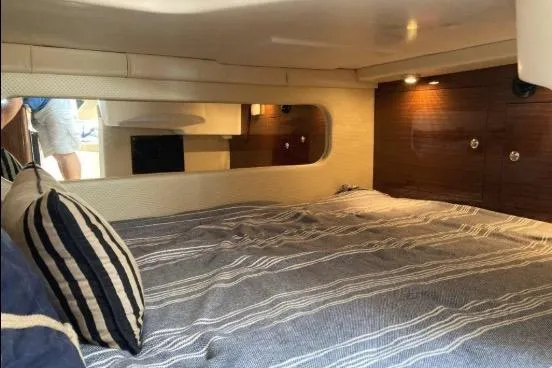 Slide: The Image of Cozy cabin interior of 2013 Regal 30 Express boat with striped bedding and wooden accents. - 30