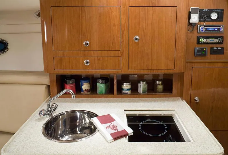 Slide: The Image of Manufacturer Provided Image: 2013 Regal 30 Express yacht kitchen with sink, stove, and wooden cabinets. - 31