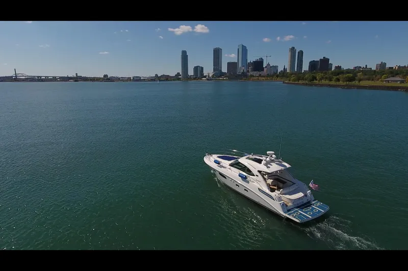 Slide: The Image of 2011 Sea Ray 470 Sundancer cruising on a calm river with city skyline backdrop. - 10