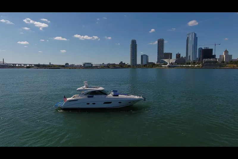Slide: The Image of A 2011 Sea Ray 470 Sundancer yacht on calm waters with a city skyline backdrop. - 16