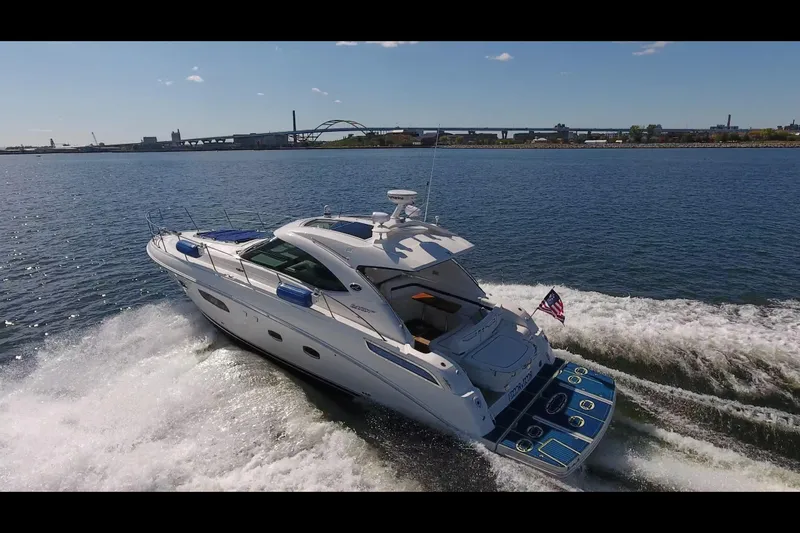 Slide: The Image of 2011 Sea Ray 470 Sundancer cruising on open water with cityscape background. - 29