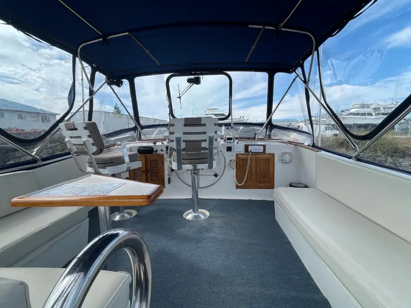Slide: The Image of 1983 Ocean Alexander TRI Cabin interior with helm, seating, and table under blue canopy. - 16