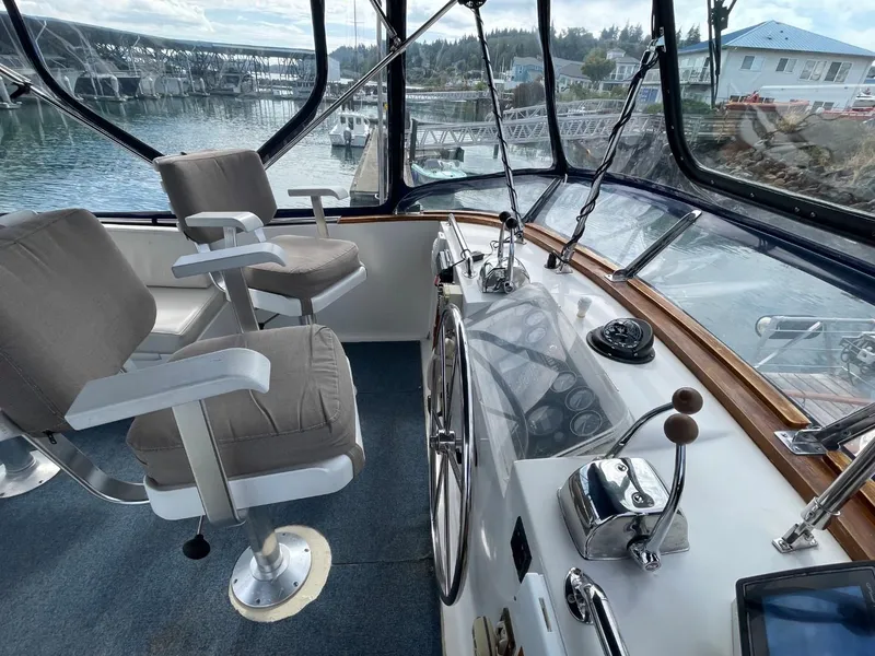 Slide: The Image of 1983 Ocean Alexander TRI Cabin helm with dual captain chairs and panoramic marina view. - 20