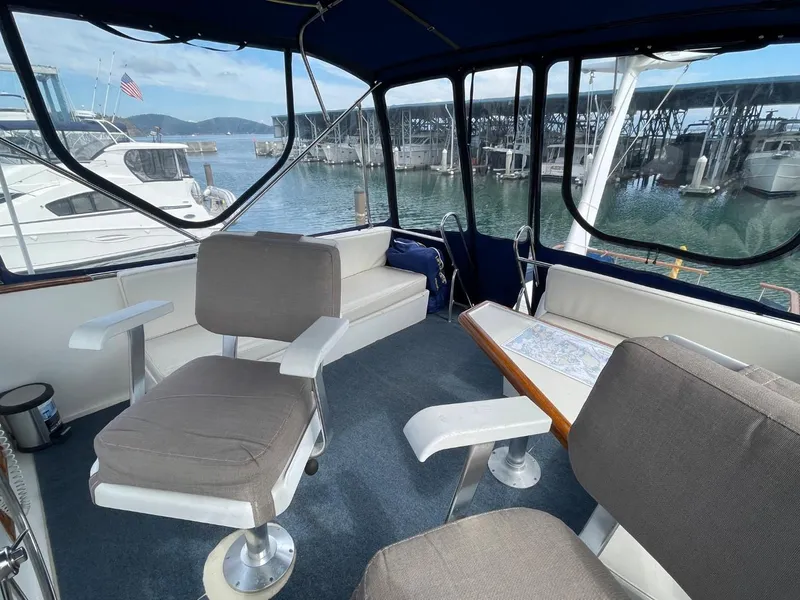 Slide: The Image of 1983 Ocean Alexander TRI Cabin interior with seating and table, docked at marina. - 26