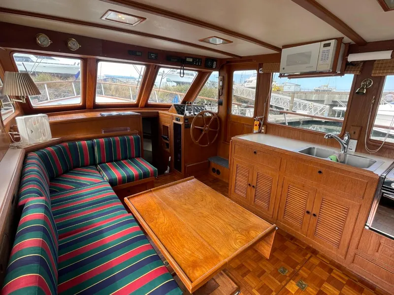 Slide: The Image of Interior of 1983 Ocean Alexander TRI Cabin with striped seating, wooden table, and helm station. - 28