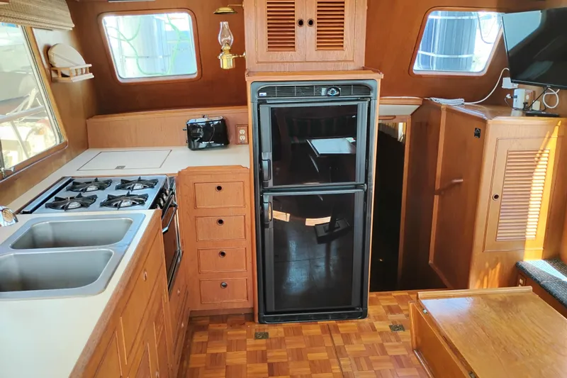 Slide: The Image of 1983 Ocean Alexander 40 Double Cabin kitchen with stove, sink, fridge, and wooden cabinetry. - 30