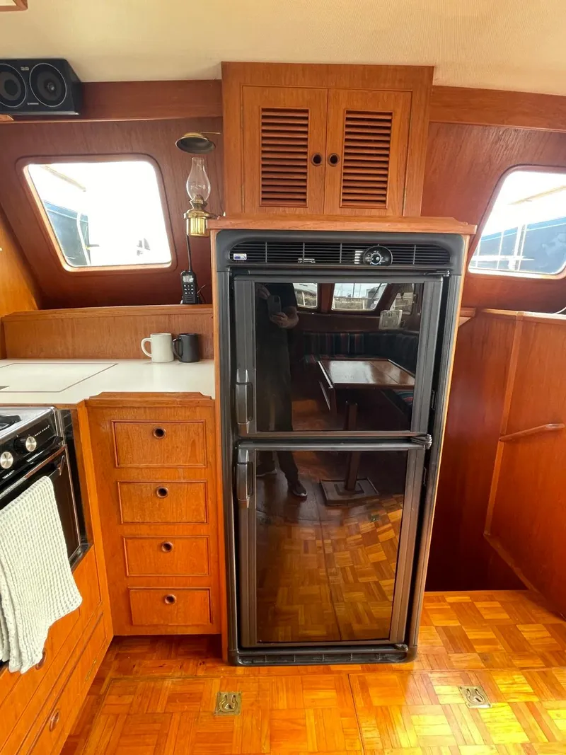 Slide: The Image of 1983 Ocean Alexander TRI Cabin kitchen with wooden cabinetry and a black refrigerator. - 33