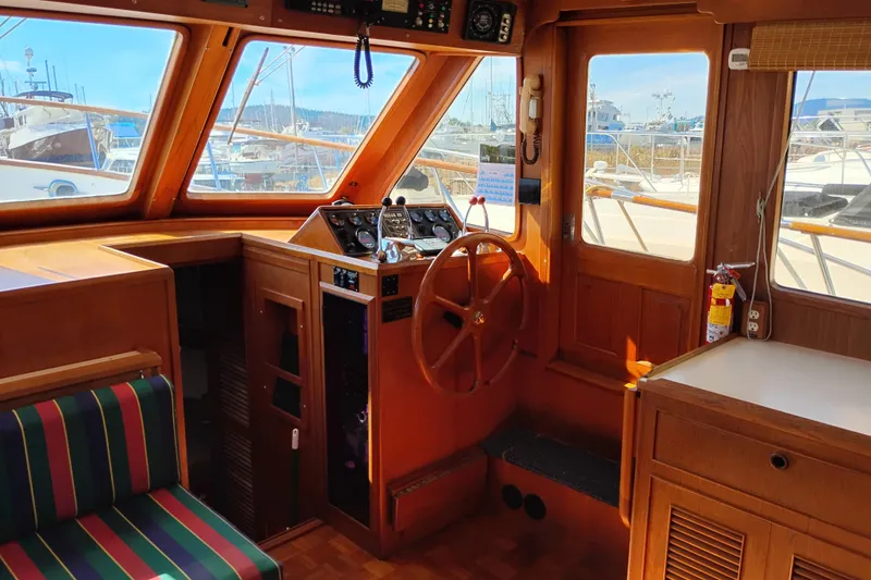 Slide: The Image of 1983 Ocean Alexander 40 Double Cabin interior with wooden helm, striped seating, and large windows. - 37