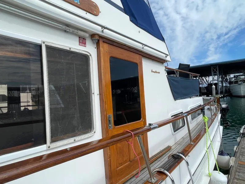 Slide: The Image of 1983 Ocean Alexander TRI Cabin yacht docked, showcasing wooden door and railing. - 5