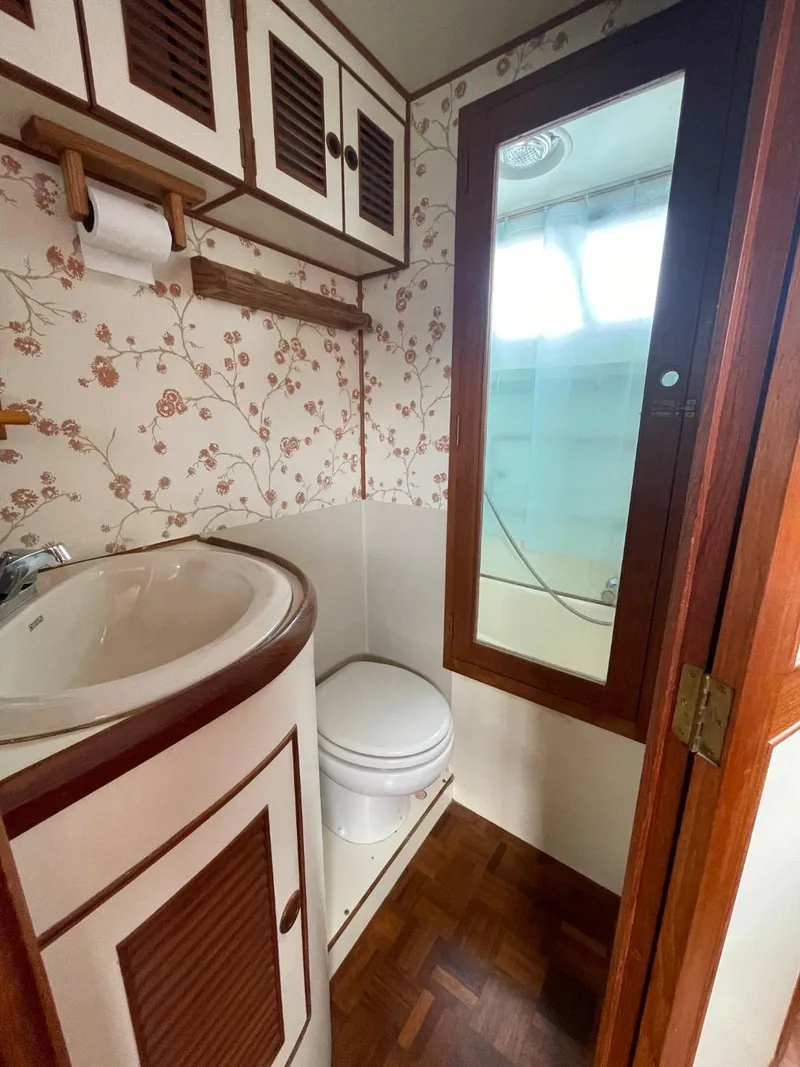 Slide: The Image of 1983 Ocean Alexander TRI Cabin bathroom with floral wallpaper and wooden accents. - 60