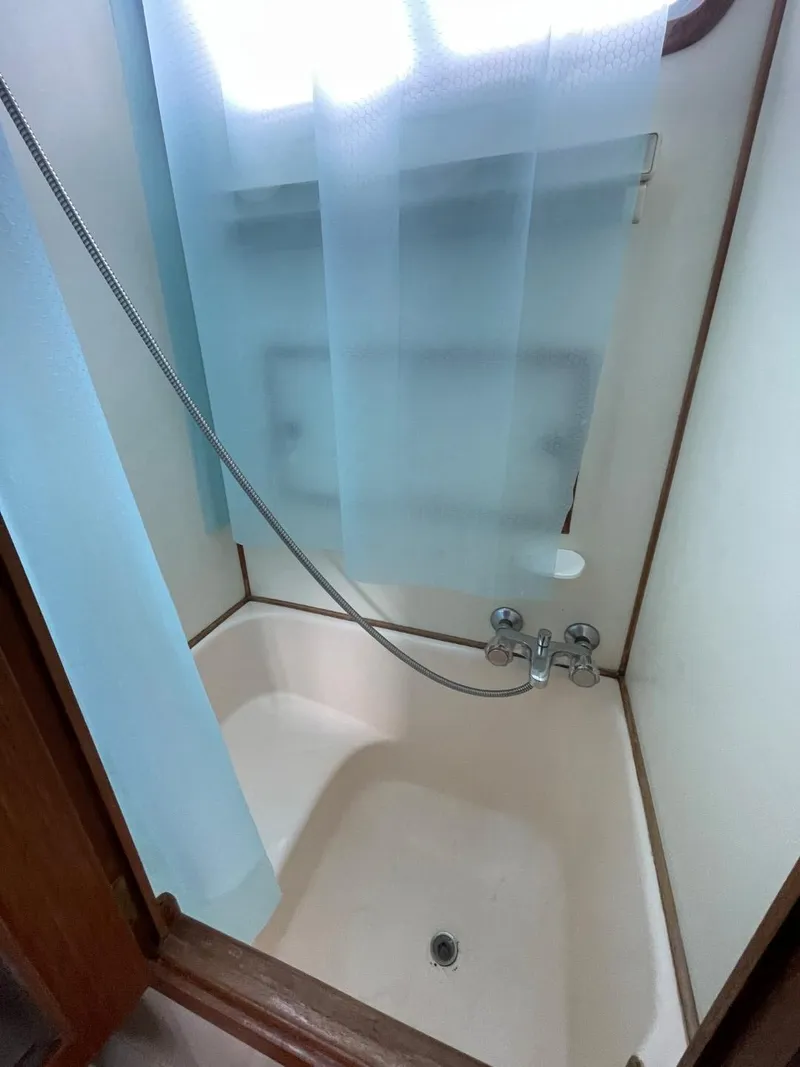 Slide: The Image of 1983 Ocean Alexander TRI Cabin shower with blue curtain and handheld showerhead. - 63