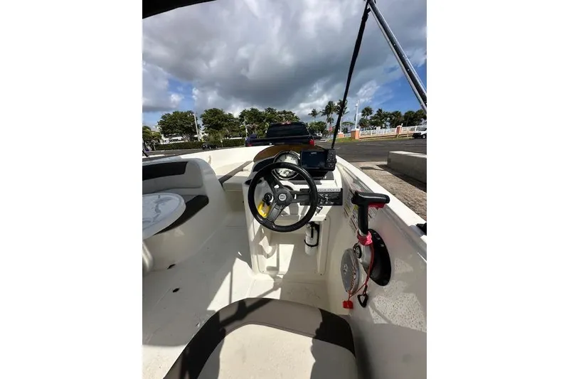 Slide: The Image of 2018 Bayliner Element E18 boat interior with steering wheel and seating under cloudy sky. - 7