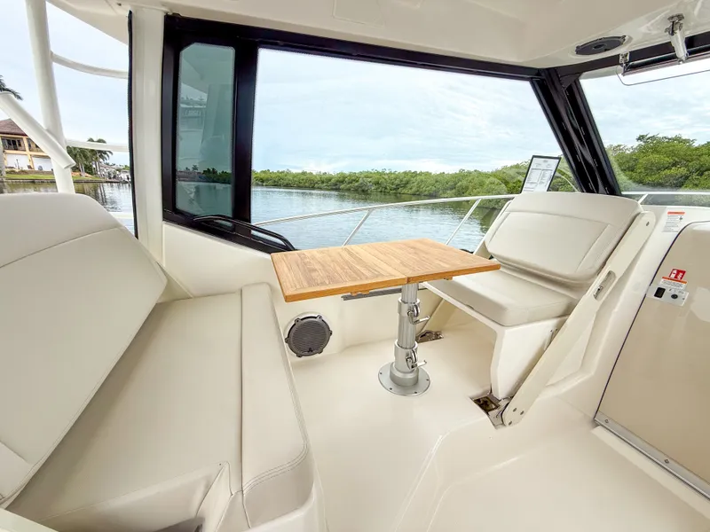 Slide: The Image of Interior of a Boston Whaler 325 Conquest with a wooden table and white seating. - 16