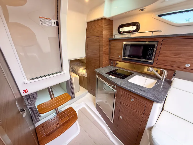 Slide: The Image of The 2027 Boston Whaler 325 Conquest cabin features a compact kitchen with a microwave and sink. - 25