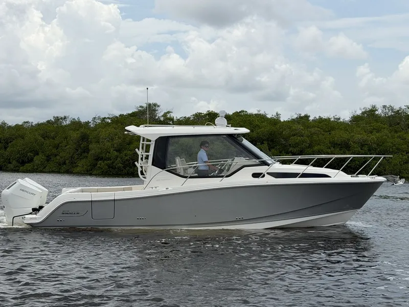 Slide: The Image of A modern motorboat with an enclosed cabin cruises on calm water, surrounded by green vegetation. - 0