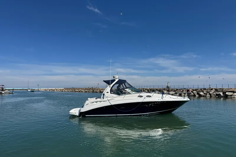 Slide: The Image of 2004 Sea Ray Sundancer 320 yacht cruising in a calm harbor under a clear blue sky. - 13