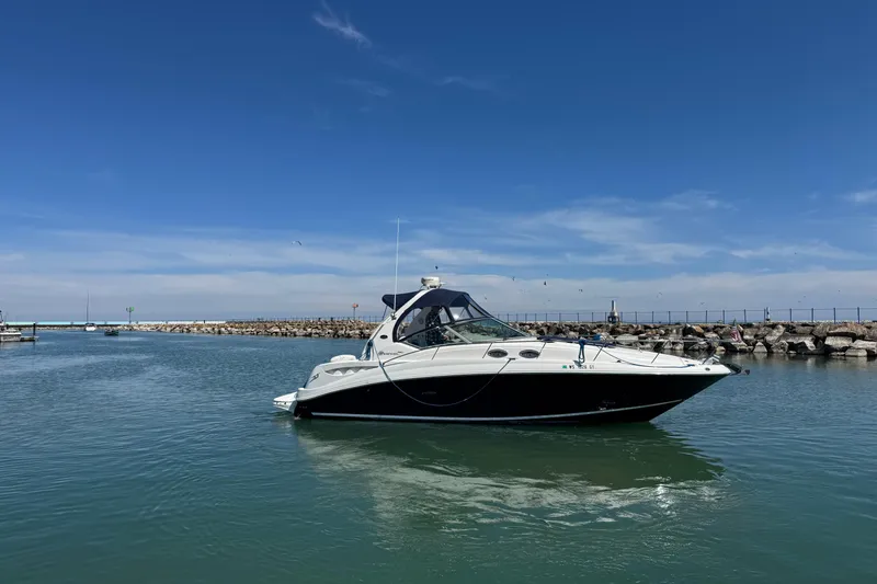 Slide: The Image of 2004 Sea Ray Sundancer 320 yacht cruising in a calm harbor under a clear blue sky. - 14