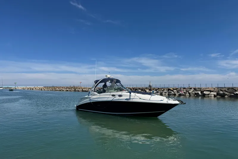 Slide: The Image of 2004 Sea Ray Sundancer 320 yacht cruising in a calm harbor under a clear blue sky. - 16
