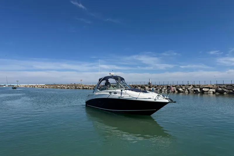 Slide: The Image of 2004 Sea Ray Sundancer 320 yacht on calm water near rocky shoreline. - 17