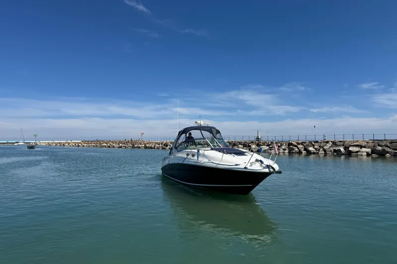 Slide: The Image of 2004 Sea Ray Sundancer 320 yacht cruising in a calm harbor under a clear blue sky. - 18