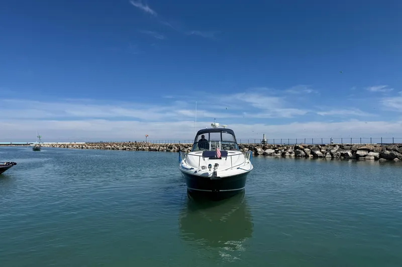 Slide: The Image of 2004 Sea Ray Sundancer 320 yacht in a calm harbor under a clear blue sky. - 20