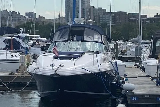 Slide: The Image of 2004 Sea Ray Sundancer 320 docked at a marina with cityscape background. - 22