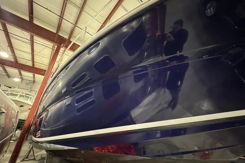 Slide: The Image of 2004 Sea Ray Sundancer 320 yacht in indoor storage, showcasing sleek blue hull design. - 26