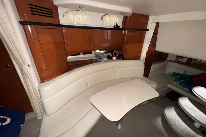 Slide: The Image of 2004 Sea Ray Sundancer 320 interior with curved seating and wooden cabinetry. - 52