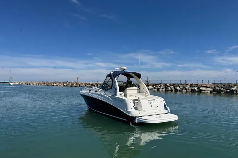 Slide: The Image of 2004 Sea Ray Sundancer 320 yacht on calm water near rocky shoreline under blue sky. - 8