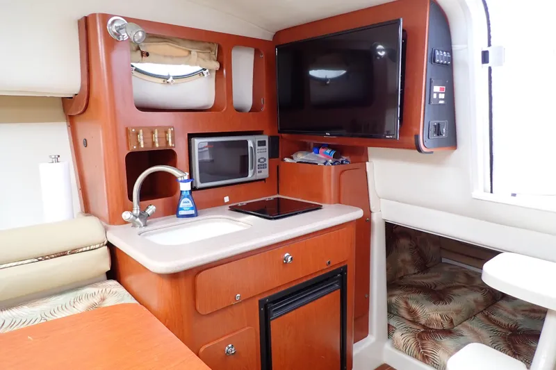 Slide: The Image of 2014 Pro-Line 32 Express cabin interior with kitchenette, microwave, TV, and cozy seating area. - 11