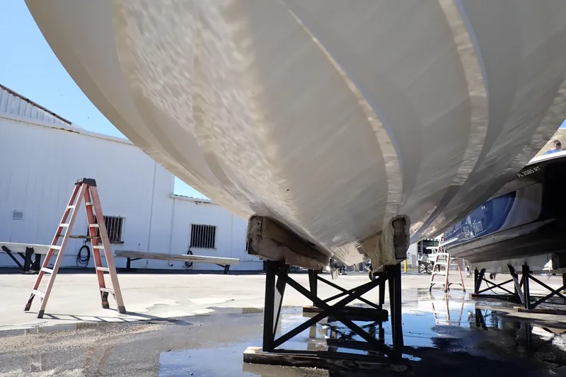 Slide: The Image of 2014 Pro-Line 32 Express boat hull on stands, with ladder nearby in a boatyard. - 126