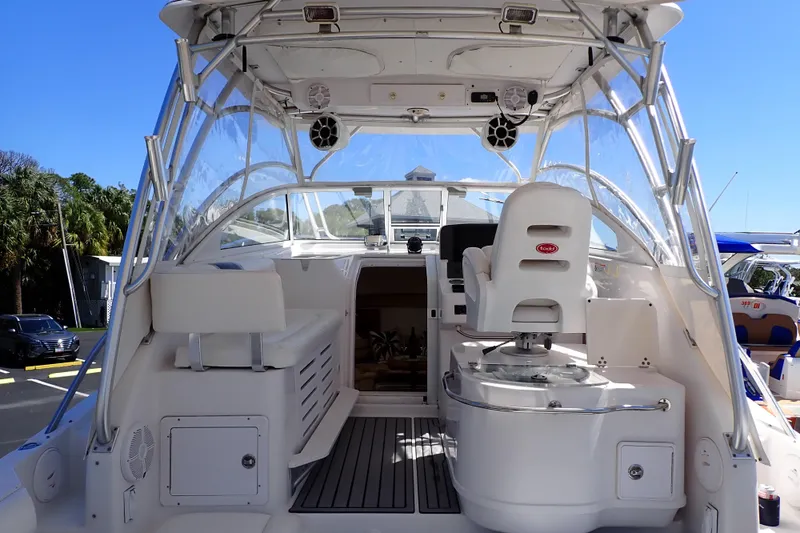 Slide: The Image of 2014 Pro-Line 32 Express boat interior with helm, seating, and clear canopy under blue sky. - 5