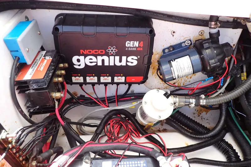 Slide: The Image of Electrical components inside a 2014 Pro-Line 32 Express boat, featuring a NOCO Genius charger. - 58