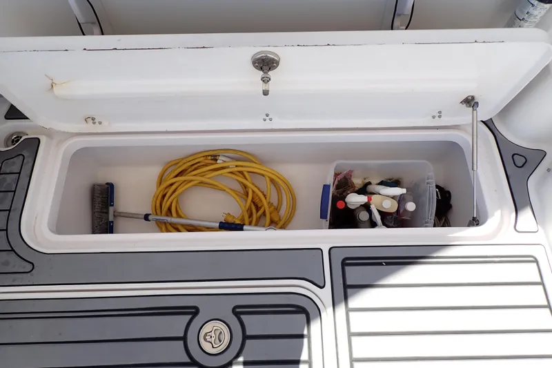Slide: The Image of Storage compartment on a 2014 Pro-Line 32 Express boat with cleaning supplies and hose. - 60