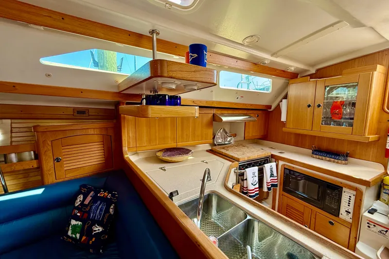 Slide: The Image of Interior of a 2002 Catalina 400 MkII yacht kitchen with wooden cabinetry and modern amenities. - 32