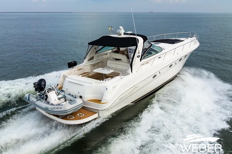 Slide: The Image of Sea Ray Sundancer 460 yacht cruising on open water, 2000 model, with a small boat attached. - 4
